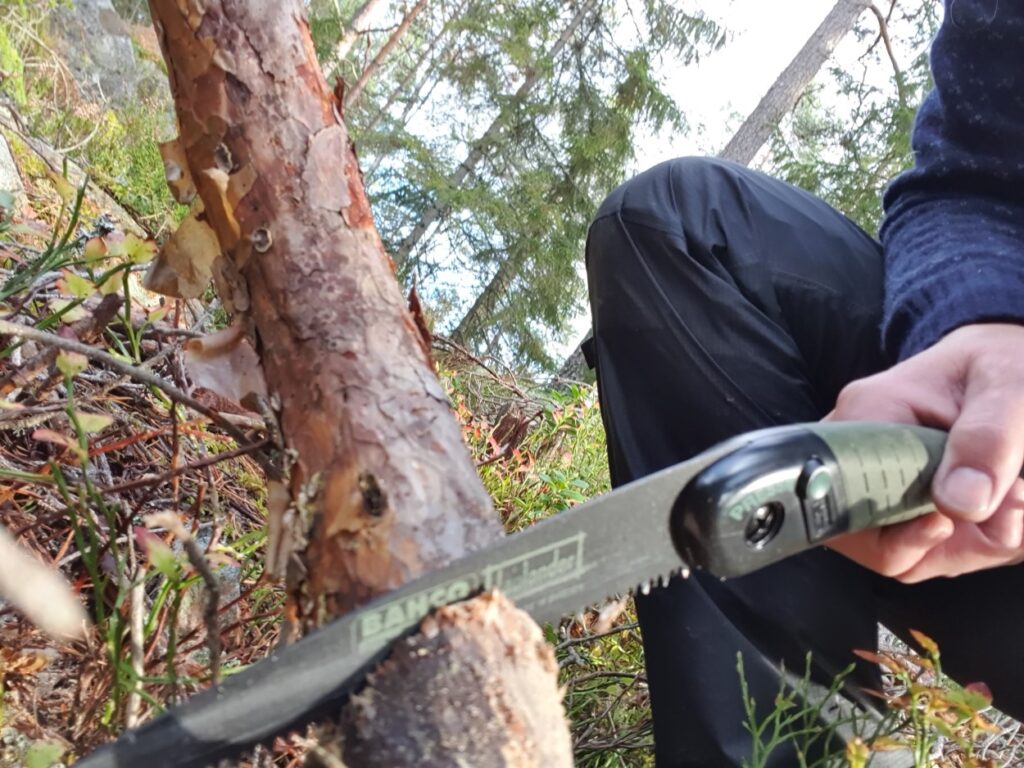 Tijdens solotrekking in Zweden is de deelnemer in een boomstam aan het zagen voor een kampvuur