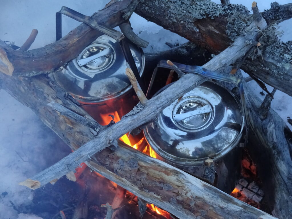 Vuur maken met billy cans bij een wintersurvival.